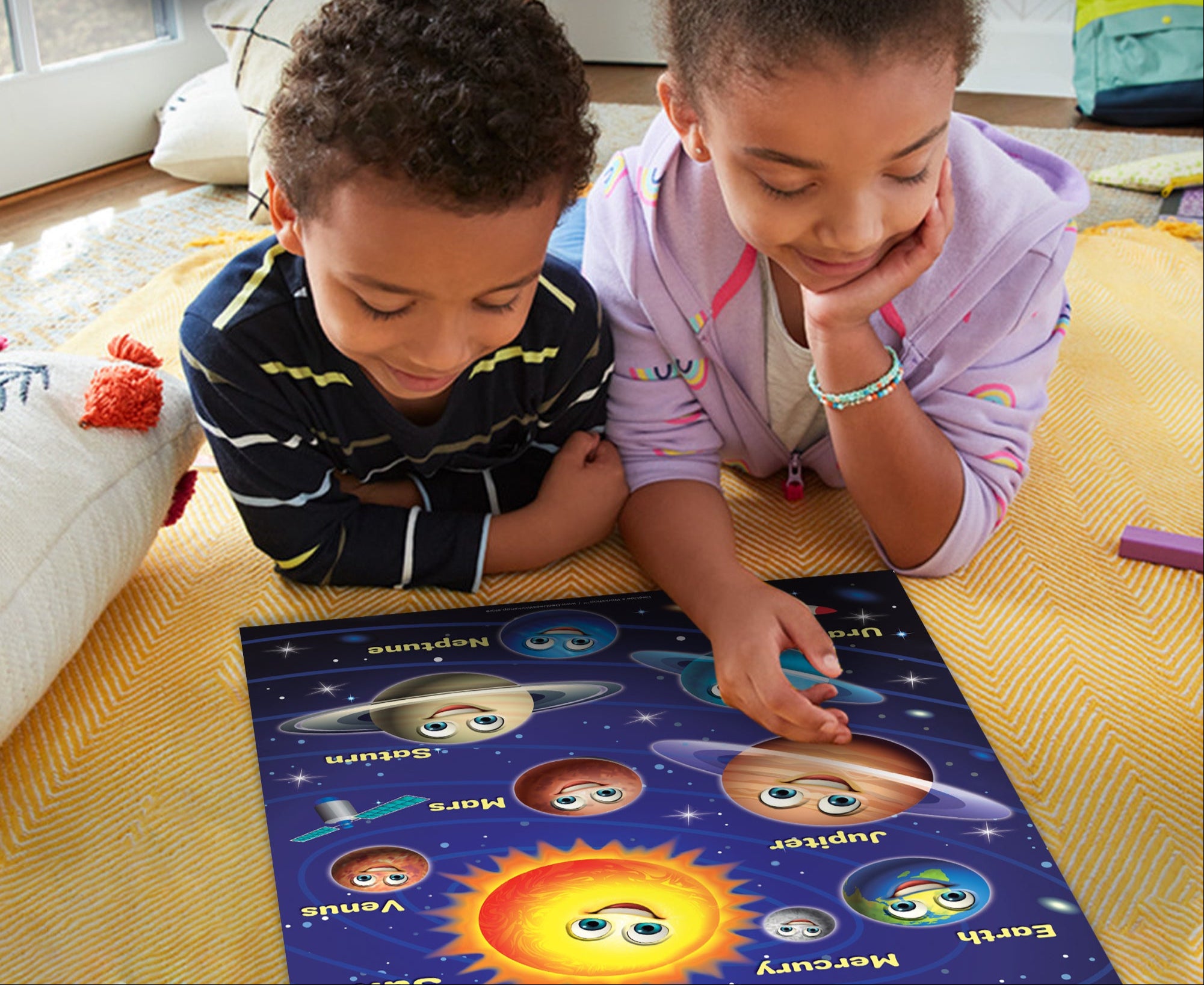 Two children playing with a solar system-themed poster on the floor
